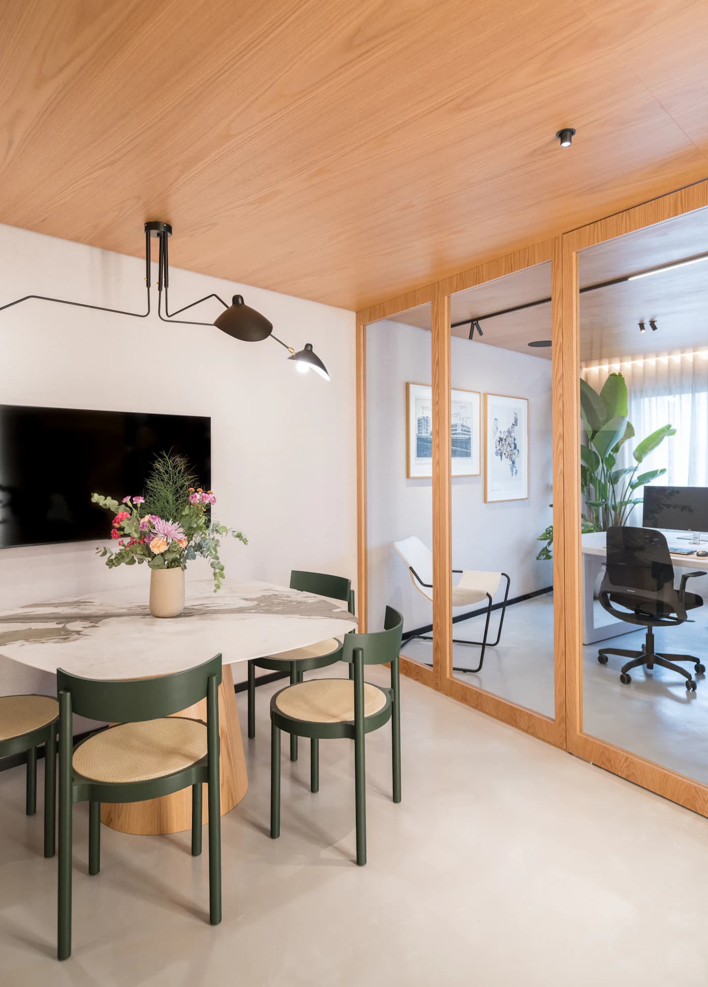 An office common area with a round table, upholstered chairs, framed art and plants